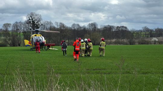 ratownicy i strażacy przenoszą rannego do helikoptera LPR