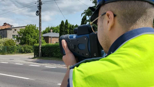 policjant z radarem mierzy prędkość kierujących