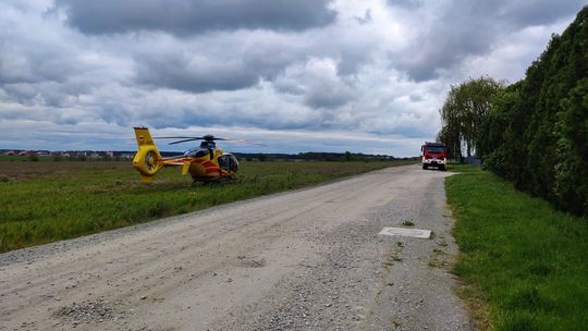 helikopter medyczny w polu i wóz strażacki w oddali na drodze polnej