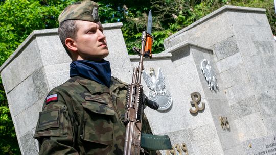 Żołnierz stojący przy pomniku żołnierza polskiego