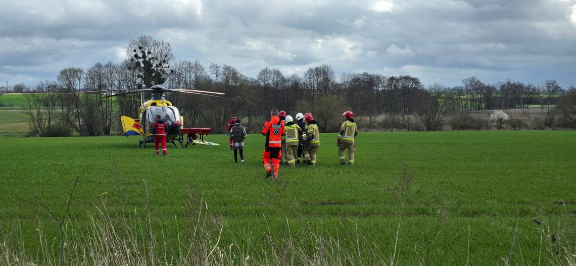 ratownicy i strażacy przenoszą rannego do helikoptera LPR