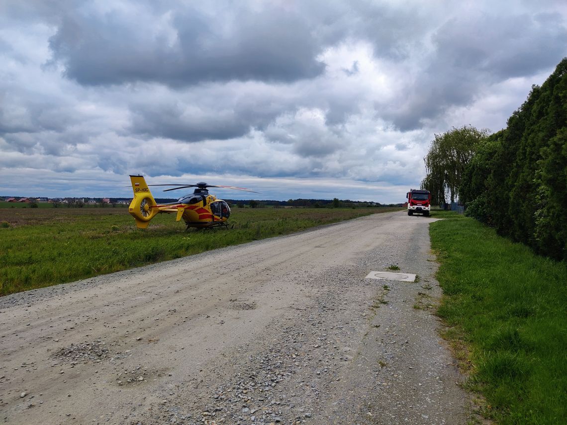 helikopter medyczny w polu i wóz strażacki w oddali na drodze polnej