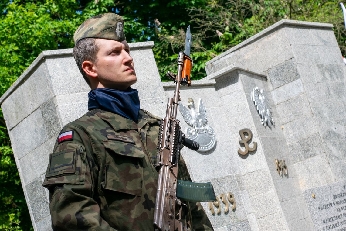 Żołnierz stojący przy pomniku żołnierza polskiego